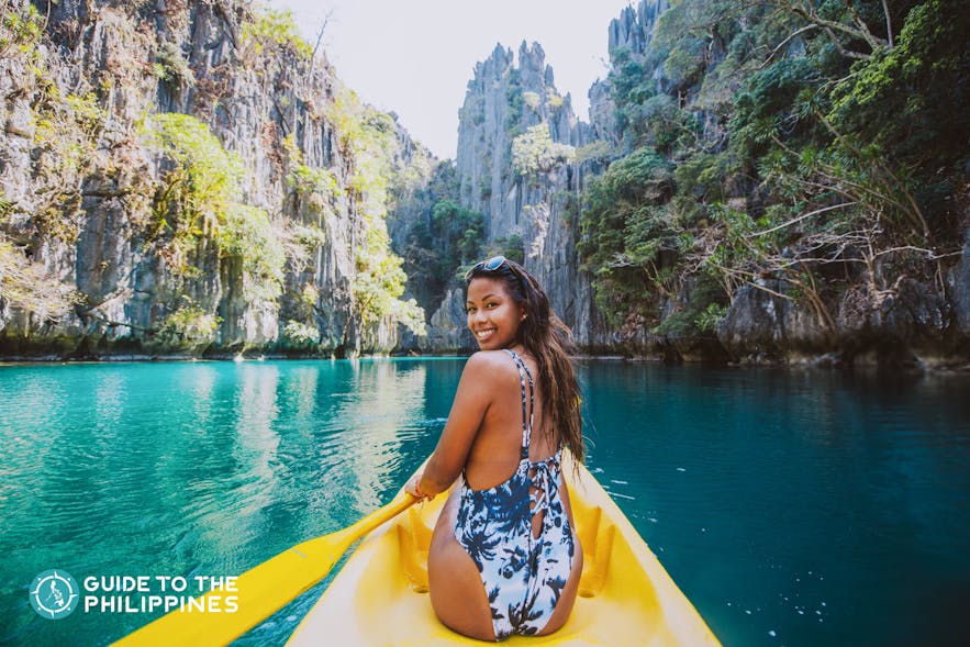 Happy female traveler kayaking along a lagoon in Coron, Palawan