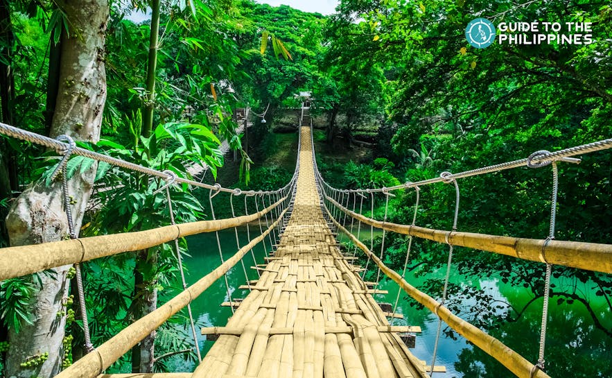 Tigbao Hanging Bridge is made of woven bamboo straps and stretches over a gently flowing river