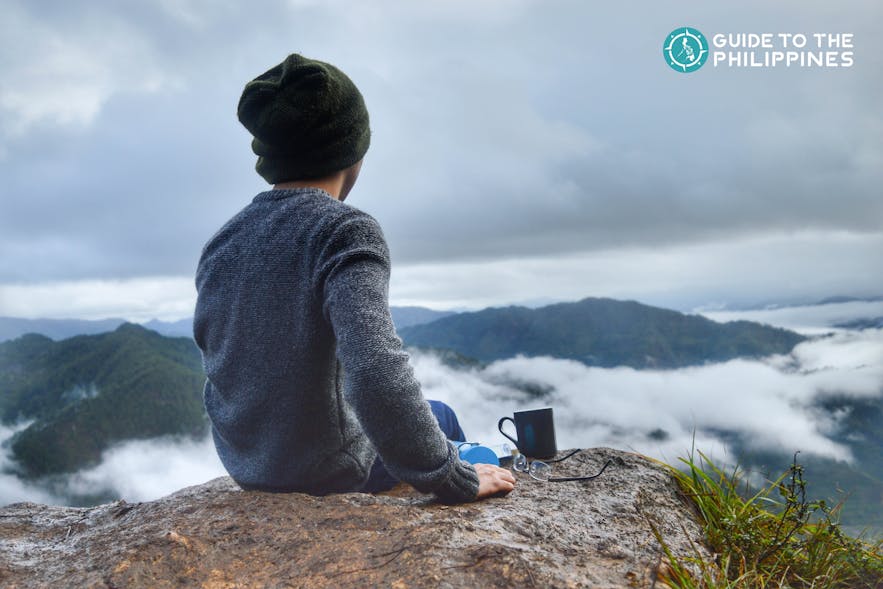 Traveler with a mug of coffee overlooking the mountain peak in Sagada