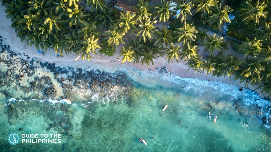 Top view of surfers in Siargao Island's clear waters