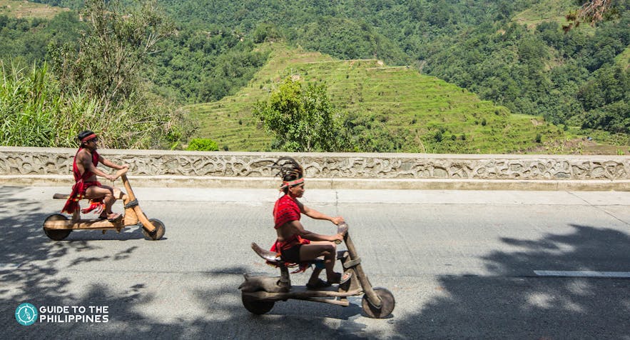 Ifugaos passing by Banaue Rice Terraces on their wooden scooters