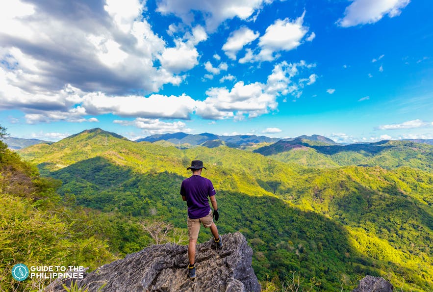 Hiker on a rock formation overlooking a lush mountain view