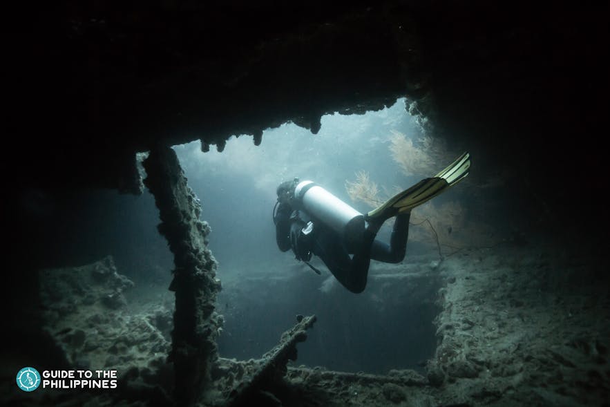 A diver exploring the wrecks of East Tangat Gunboat