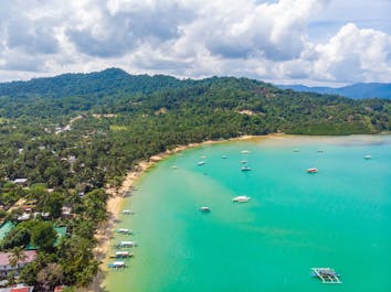 Aerial view of the boats going to the beautiful beach of Port Barton in Palawan
