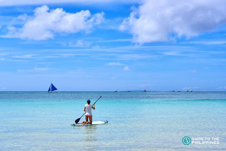 A woman paddleboarding in the blue waters of Boracay