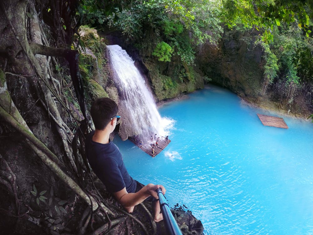 A man standing on a cliff in Kawasan Falls