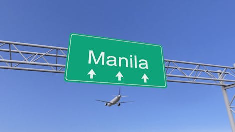 A plane flying over a Manila sign