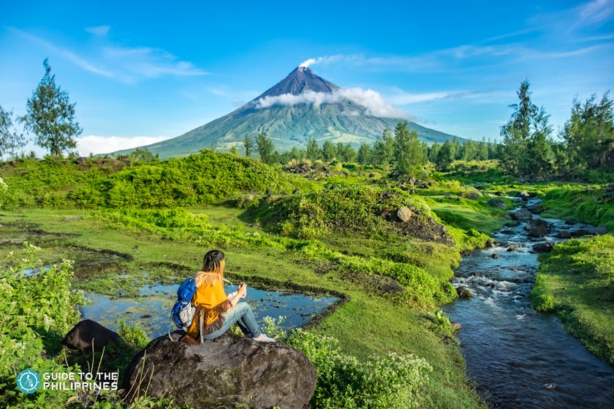 Hiker looks at Mayon Volcano in the distance
