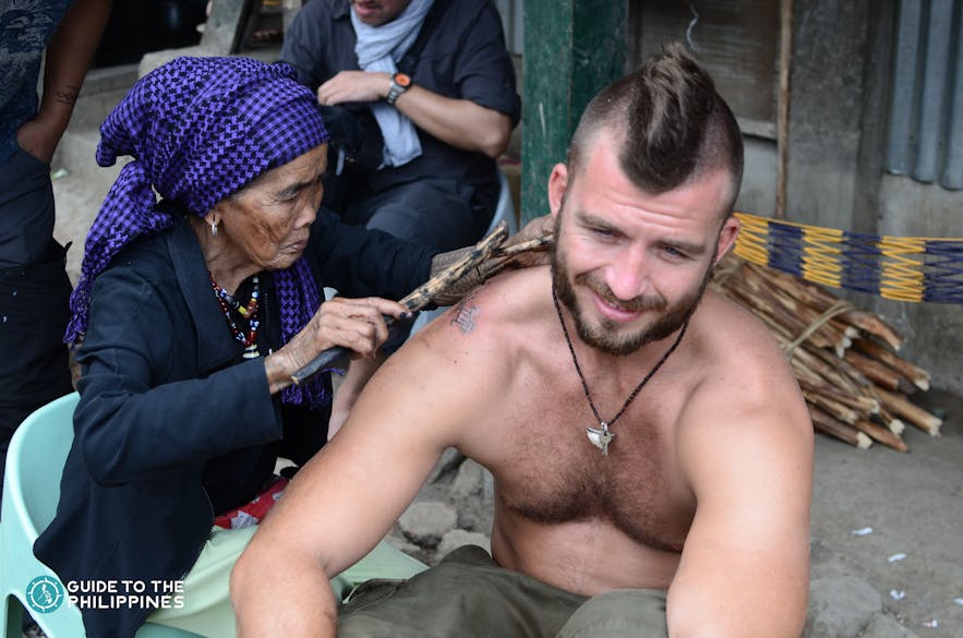 Apo Whang-Od creating a tattoo on a tourist in Buscalan Village