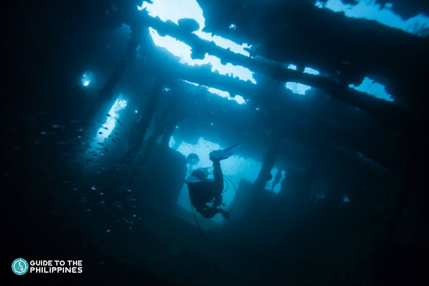 Scuba diver exploring world war II shipwreck in Coron