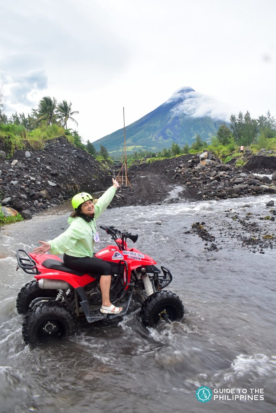 Traveler crossing river by Mayon Volcano