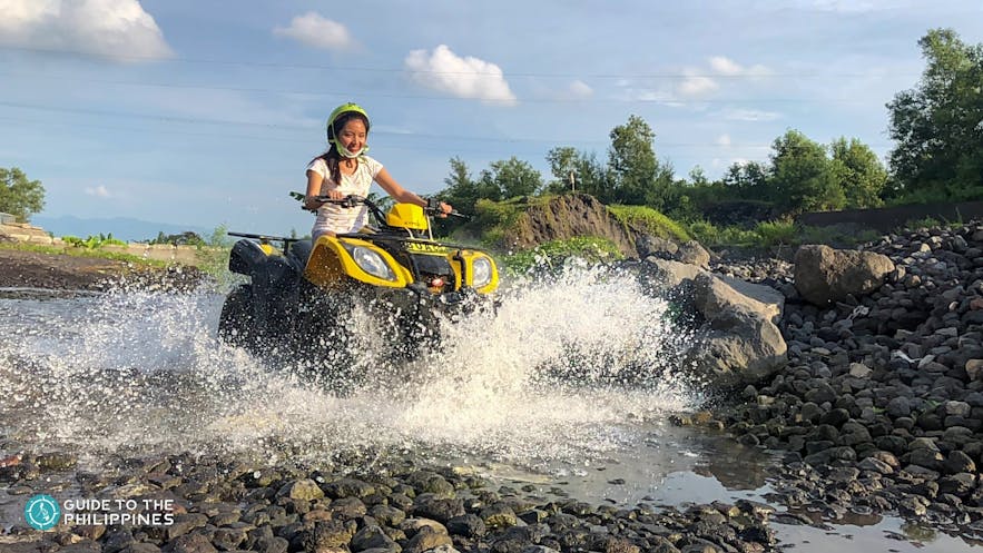 Woman riding an ATV through a river