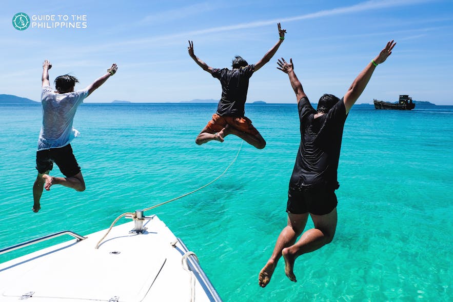 Friends jumping from boat to the sea