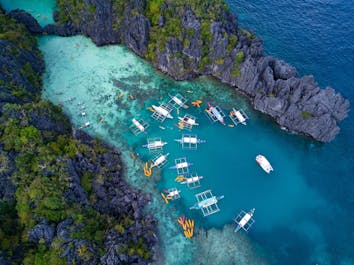 See towering karst cliffs surrounding the clear waters of Big Lagoon