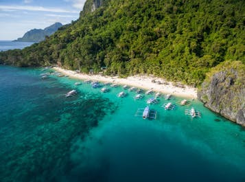 Travel to the beautiful beach below those dramatic limestone cliffs El Nido is famous for at Seven Commandos Beach