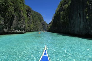 Witness the striking blue waters surrounded by dark limestone cliffs at Big Lagoon El Nido